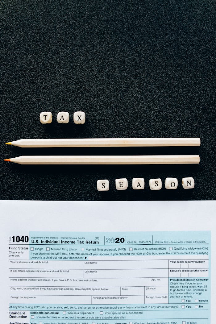 gallery-6 Creative composition featuring 1040 tax form, pencils, and letters spelling Tax Season on black background.
